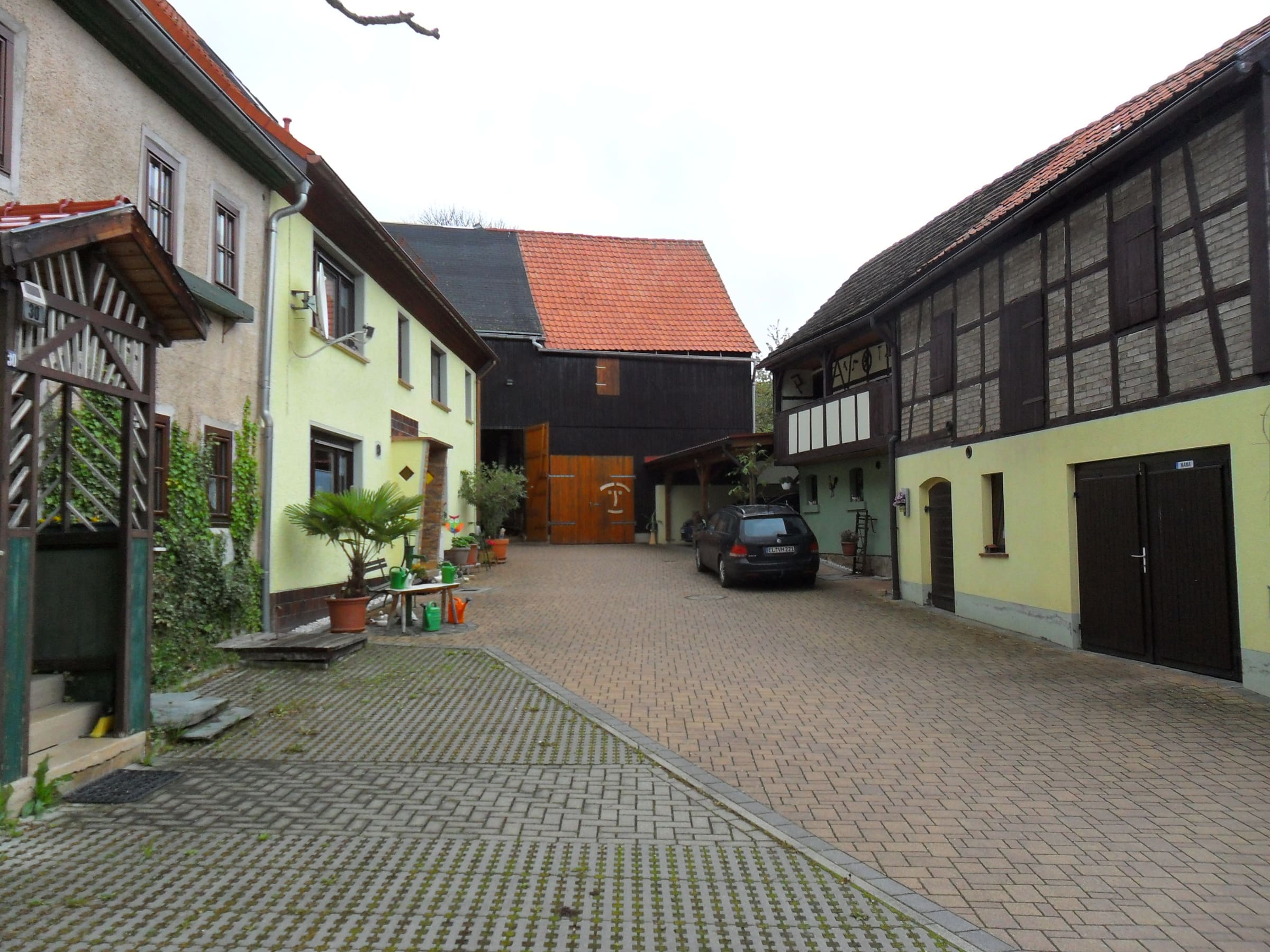 Gepflasterte Hofeinfahrt zwischen Wohnhaus und alter Fachwerkscheune