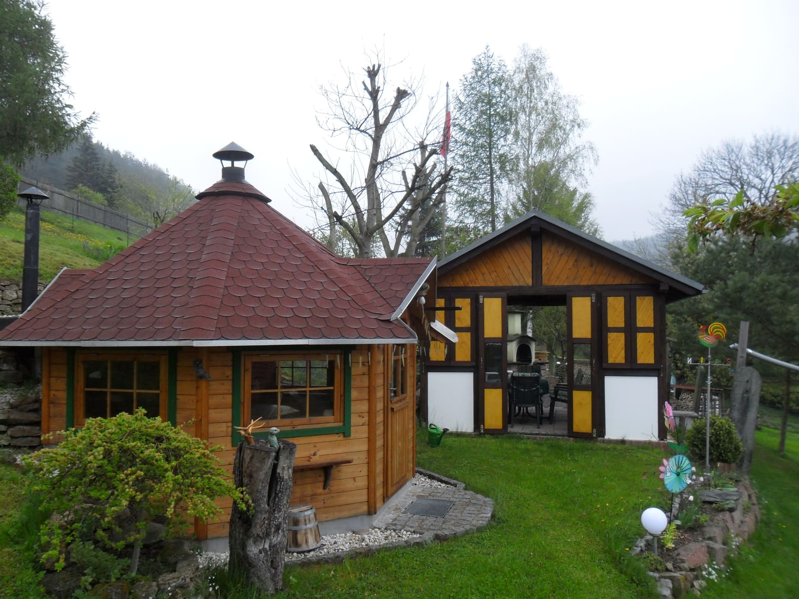 Grillkota und Gartenhaus an einem Nebelmorgen, im Hintergrund das Tal